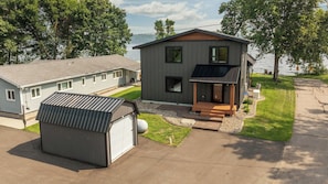 A two-story house with a garage, a covered porch, and a view of a lake.