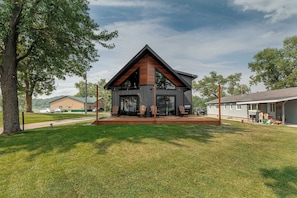 A modern two-story house with a large porch, surrounded by a well-maintained lawn and trees. - Great MEA and Fall Getaway Lakefront Cabin (Cushing)