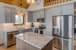 A modern kitchen with grey cabinets, stainless steel appliances, and a large island. - Great MEA and Fall Getaway Lakefront Cabin (Cushing)
