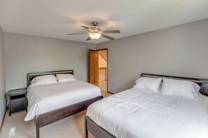 A bedroom with two beds, a ceiling fan, and a door leading to another room. - Great MEA and Fall Getaway Lakefront Cabin (Cushing)