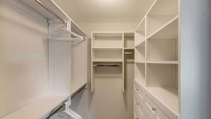 A walk-in closet with open shelves, a hanging rod, and a built-in dresser.