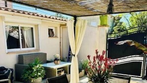 Eine Terrasse im Freien mit einem runden Tisch, Stühlen und Kübelpflanzen.