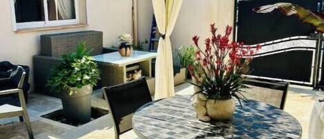 An outdoor patio with a round table, chairs, and potted plants.