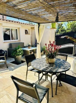 Eine Terrasse im Freien mit einem runden Tisch, Stühlen und Kübelpflanzen.