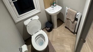 Une petite salle de bain avec des toilettes, un lavabo et une fenêtre.