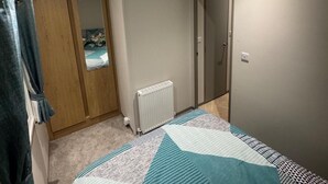 Une chambre à coucher avec un lit, un radiateur, une armoire et une porte.