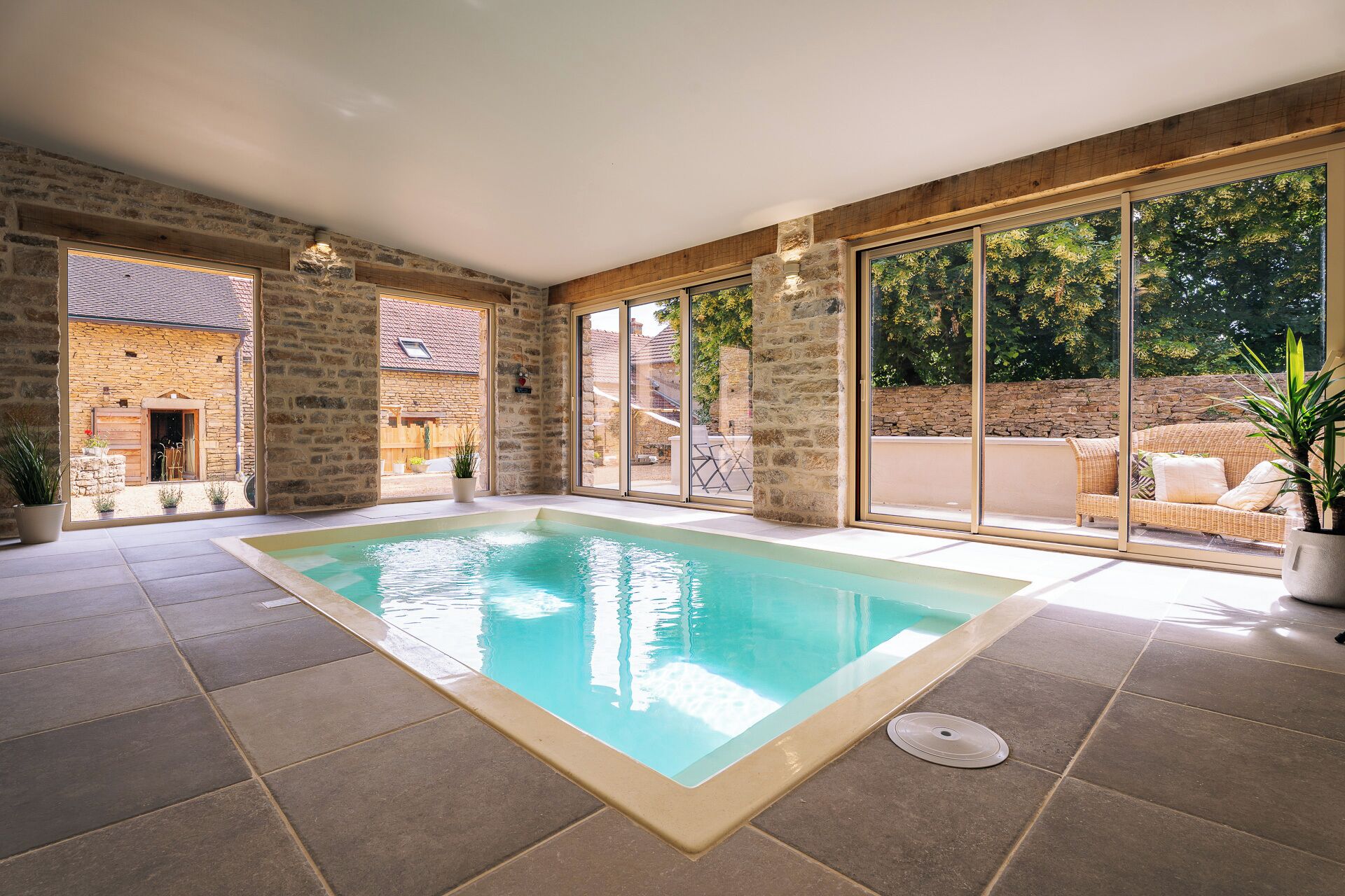 A swimming pool with stone walls and large windows.