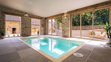 A swimming pool with stone walls and large windows.