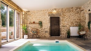Un espace piscine agrémenté de murs en pierre, de meubles en osier et de plantes en pot.