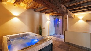 A spa area with a hot tub, wooden beams, and a tiled floor.