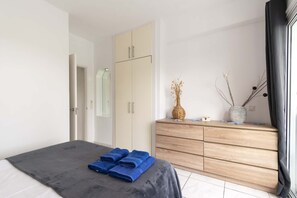 Ein Schlafzimmer mit Bett, Kleiderschrank, Kommode und Fenster.