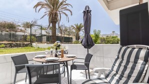 An outdoor patio with a round table set for dining, surrounded by chairs and a sofa. - Club Atlantis 150 - One Bed (Costa Adeje)
