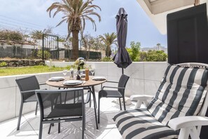 Eine Terrasse im Freien mit einem runden Esstisch, umgeben von Stühlen und einer Couch.