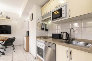 A modern kitchen with white cabinets, stainless steel appliances, a coffee maker, and a kettle. - Club Atlantis 150 - One Bed (Costa Adeje)