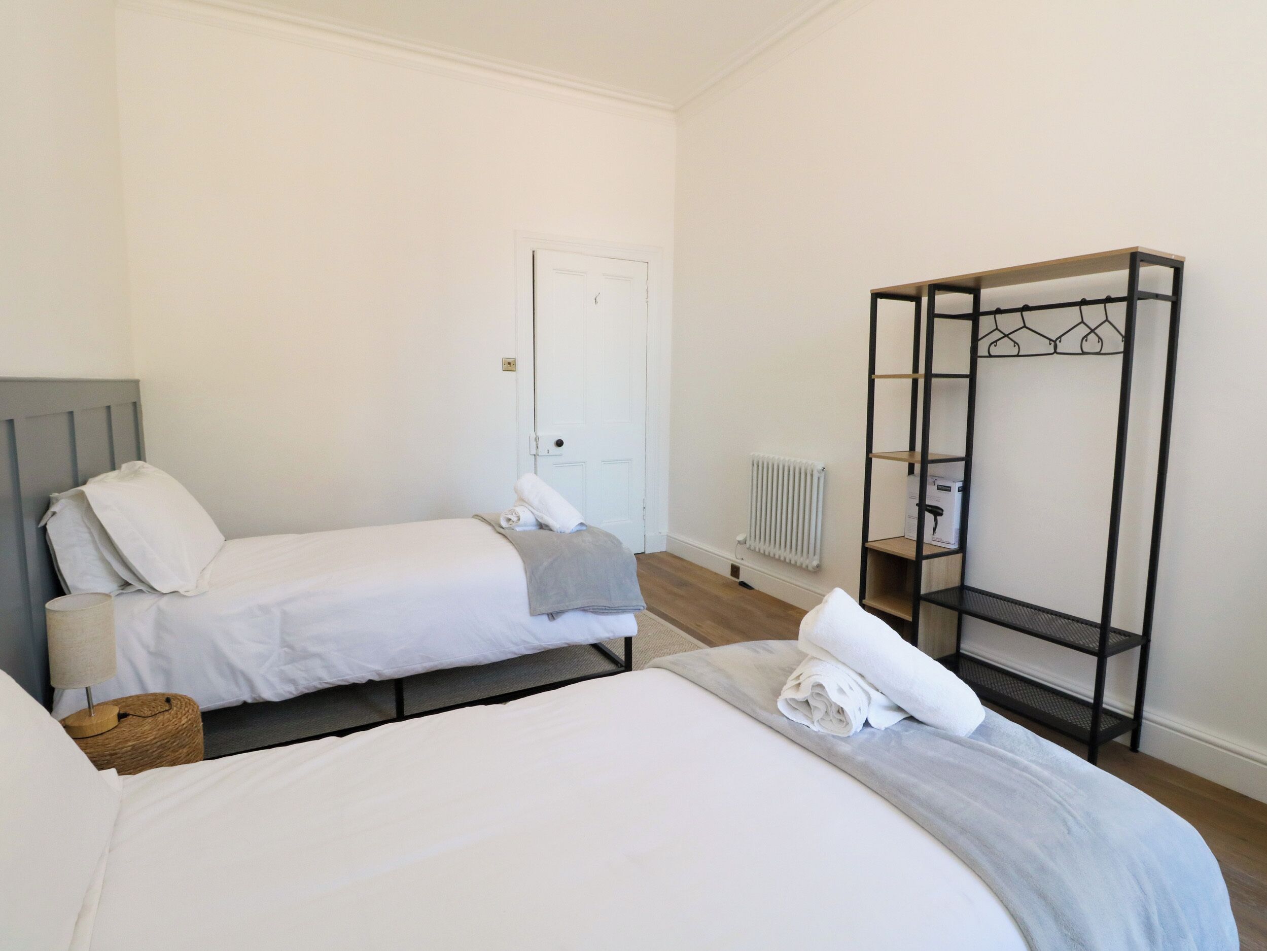 Une chambre d’hôtel avec deux lits, une armoire, un radiateur et une petite table.