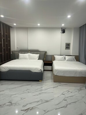 A hotel room with a large bed, a smaller bed, a wardrobe, a nightstand, and a wall-mounted light fixture. - Cozy Corner Beach Hotel (Phu Quoc)