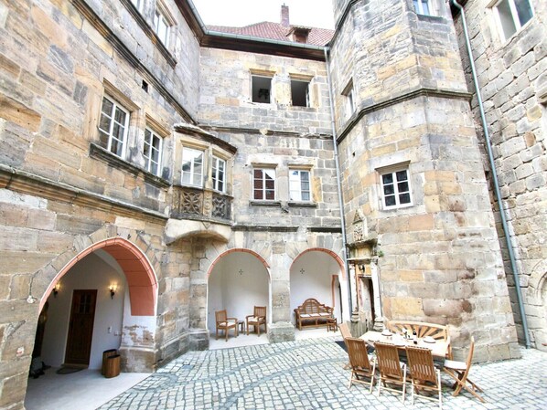 A courtyard with stone walls, arched doorways, and a table with chairs.