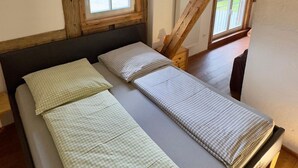 A room with a bed, wooden beams, a window, and a view of the outdoors.