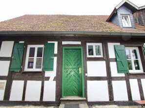 A traditional half-timbered house with a green door, white shutters, and a tiled roof. - Schlossgut Franken (Redwitz an der Rodach)