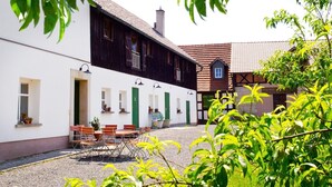 A courtyard with a white building, a black building, and a red-roofed house. - Schlossgut Franken (Redwitz an der Rodach)