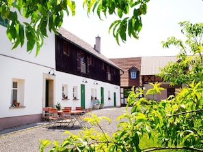 En innergård med en vit byggnad, en svart byggnad och ett hus med rött tak.