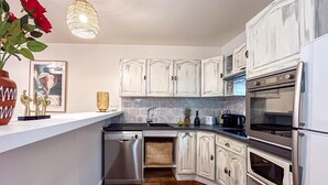 A kitchen with white cabinets, stainless steel appliances, and a tiled backsplash. - Superbe appartement place des lices (Saint-Tropez)