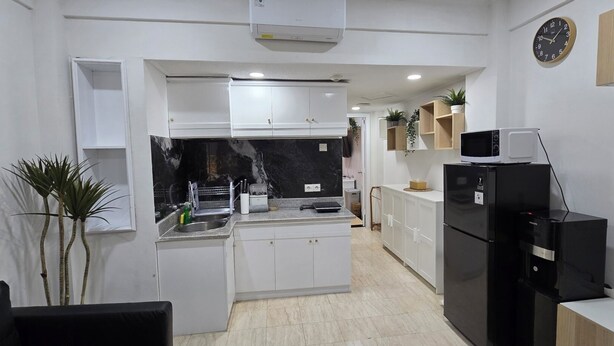 A modern kitchen with white cabinets, a black refrigerator, and a microwave.