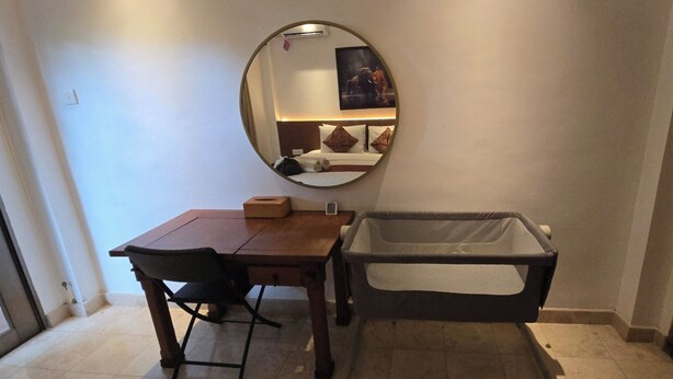 Una habitación de hotel con un escritorio de madera, una silla, una mesita con una caja de pañuelos, un espejo grande y una bañera.