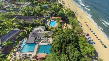 An aerial view of a resort with a swimming pool, beach, and ocean.