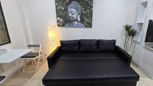 Una cocina moderna con un sofá negro, una estatua de Buda y un lavabo.