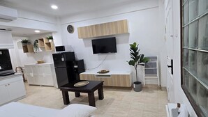Cocina compacta con comedor, televisor de pantalla plana sobre la encimera y una planta en maceta.