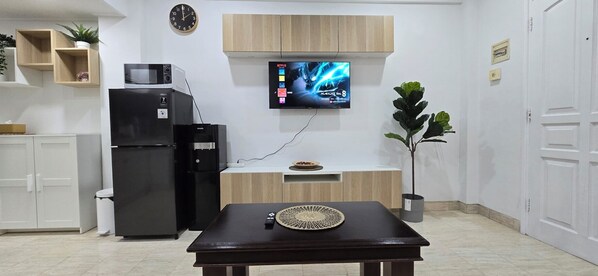 Una cocina moderna con microondas integrado, refrigerador, lavamanos y un armario de madera sobre la encimera.