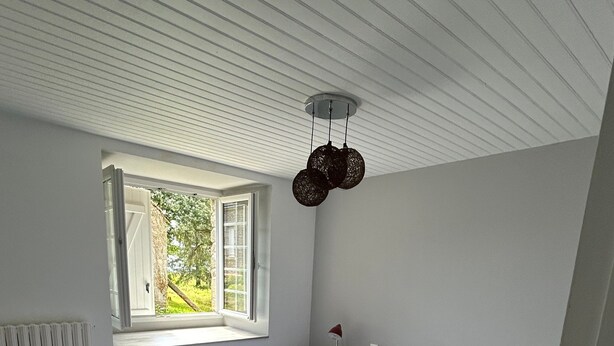 A bedroom with a large bed, a window, a bedside table, and a radiator. - Holiday Home 'Bienvenue – Former Farmhouse 4 to 6 p' with Terrace, Garden & Wi-Fi (Ploërdut)