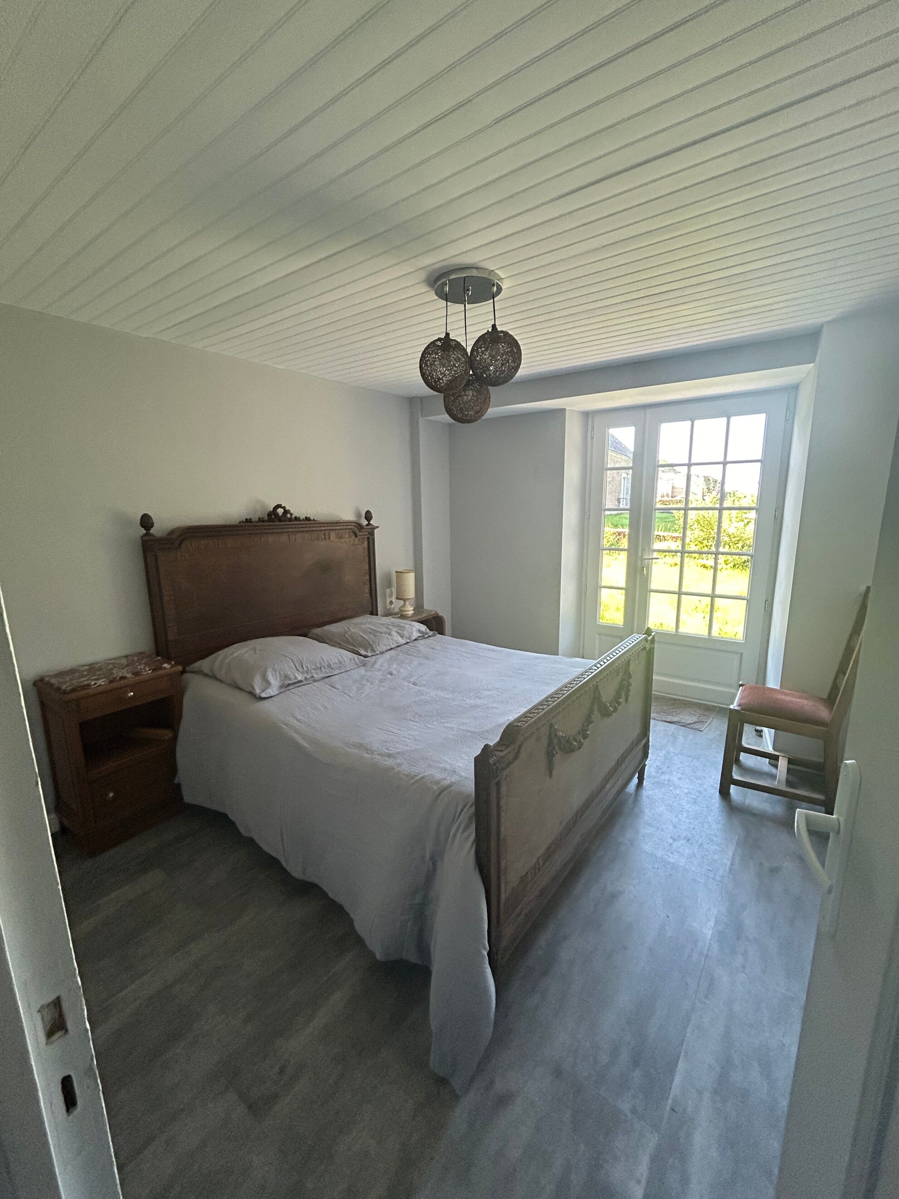 Un dormitorio con cama, mesita de noche, cómoda y ventana con vistas.