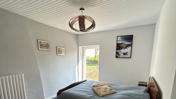 Ein Schlafzimmer mit einem Bett, einem Nachttisch, einer Lampe, einer Heizung und gerahmten Bildern an der Wand.