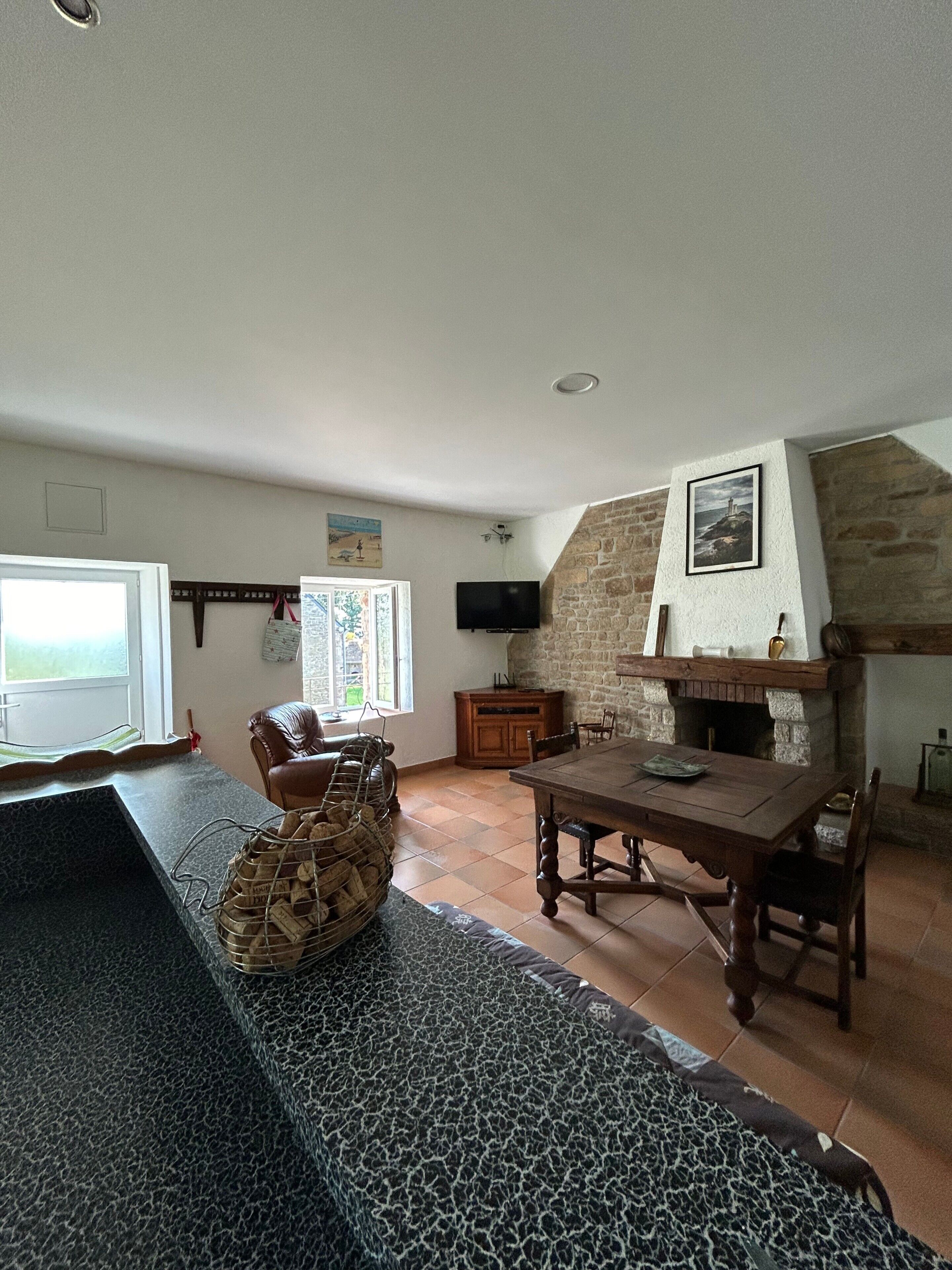 A spacious living area with a stone fireplace, a dining table, and a seating arrangement.