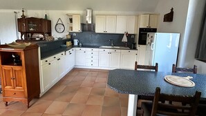 A kitchen with white cabinets, a dining table with chairs, and a refrigerator.