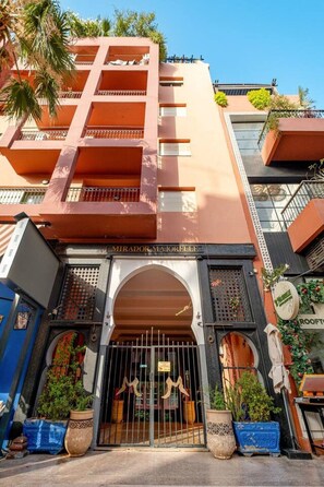 A multi-story building with a prominent entrance featuring a large archway and a sign reading 'MIRADOR MAJORELLE'. - Superbe face Jardin Majorelle | Piscine & Parking (Marrakesh)