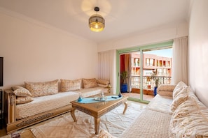 A living room with a sofa set, a coffee table, and a view of a balcony with plants. - Superbe face Jardin Majorelle | Piscine & Parking (Marrakesh)
