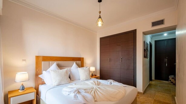 Ein Hotelzimmer mit einem großen Bett, einem Holzkopfteil, Nachttischlampen und einem Kleiderschrank.