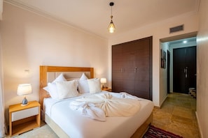 Una camera d'albergo con un letto grande, una testiera in legno, lampade ai comodini e un armadio.