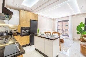Een moderne keuken met een centraal eiland, een ingebouwde oven en een groot raam met uitzicht op de stad.