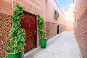 A narrow alleyway with a wooden door and potted plants on either side. - Riad Jad • 5BR • Pool • Breakfast • Rooftop (Marrakesh)