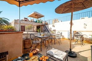 An outdoor patio with a table and chairs, a small staircase, and a railing. - Riad Jad • 5BR • Pool • Breakfast • Rooftop (Marrakesh)