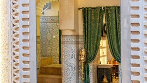 Ein traditionelles marokkanisches Interieur mit einer Wand aus farbenfrohen Fliesen, einer hölzernen Bank und einer dekorativen Laterne.