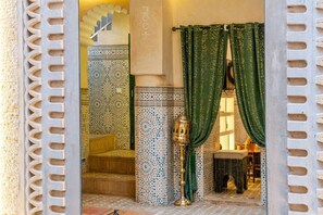 A traditional Moroccan interior with a patterned tile wall, a wooden bench, and a decorative lantern. - Riad Jad • 5BR • Pool • Breakfast • Rooftop (Marrakesh)