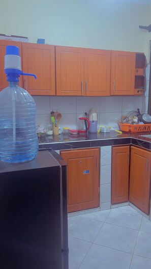 A kitchen with wooden cabinets, a large water dispenser, and various kitchen utensils.