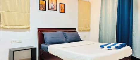 A bedroom with a bed, a bedside table, a wall-mounted air conditioner, and curtains.