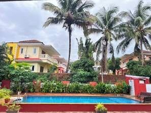 Ein Wohngebiet mit Swimmingpool, Palmen und Häusern mit Balkonen.