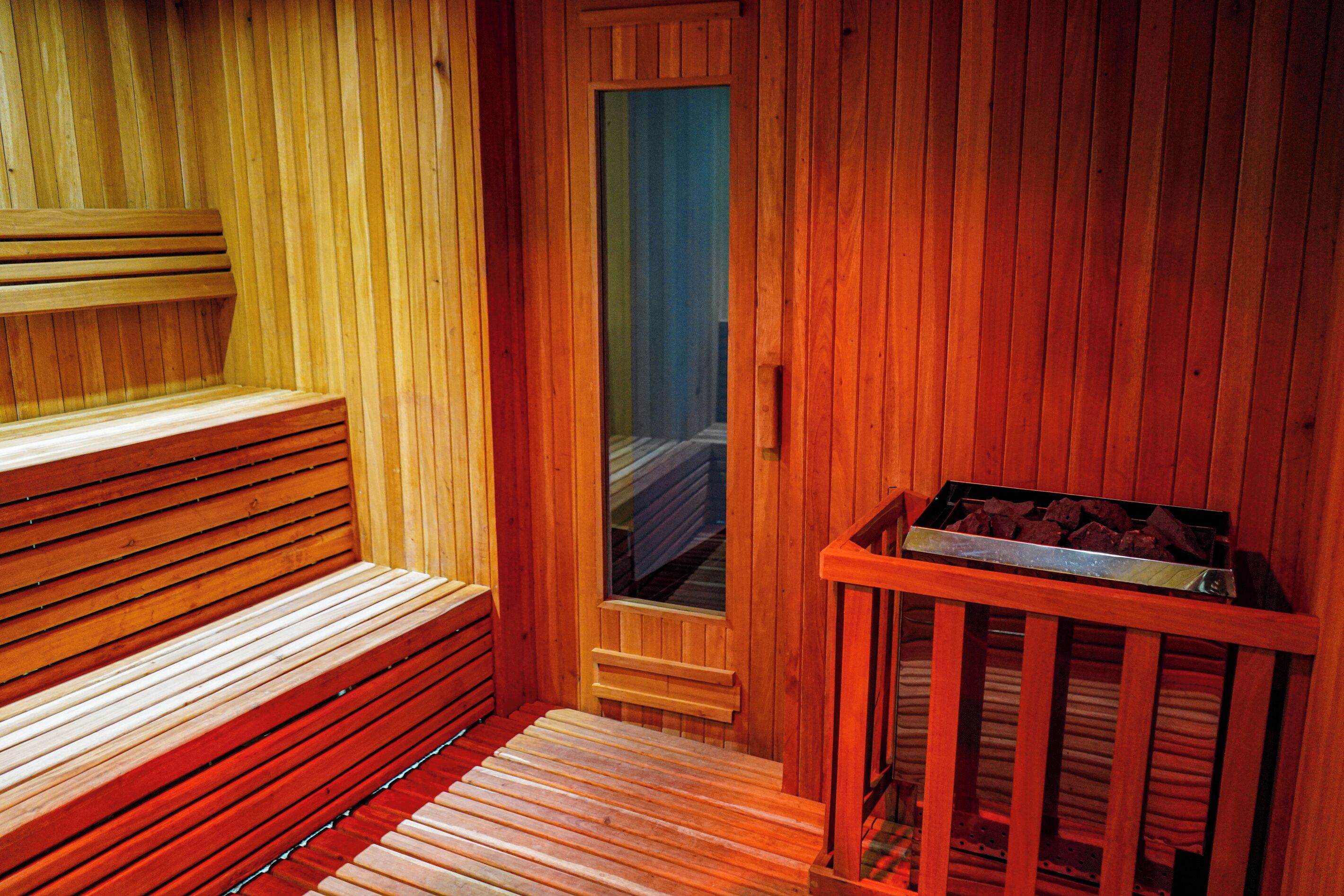 A sauna with wooden benches and a bench with a metal tray.